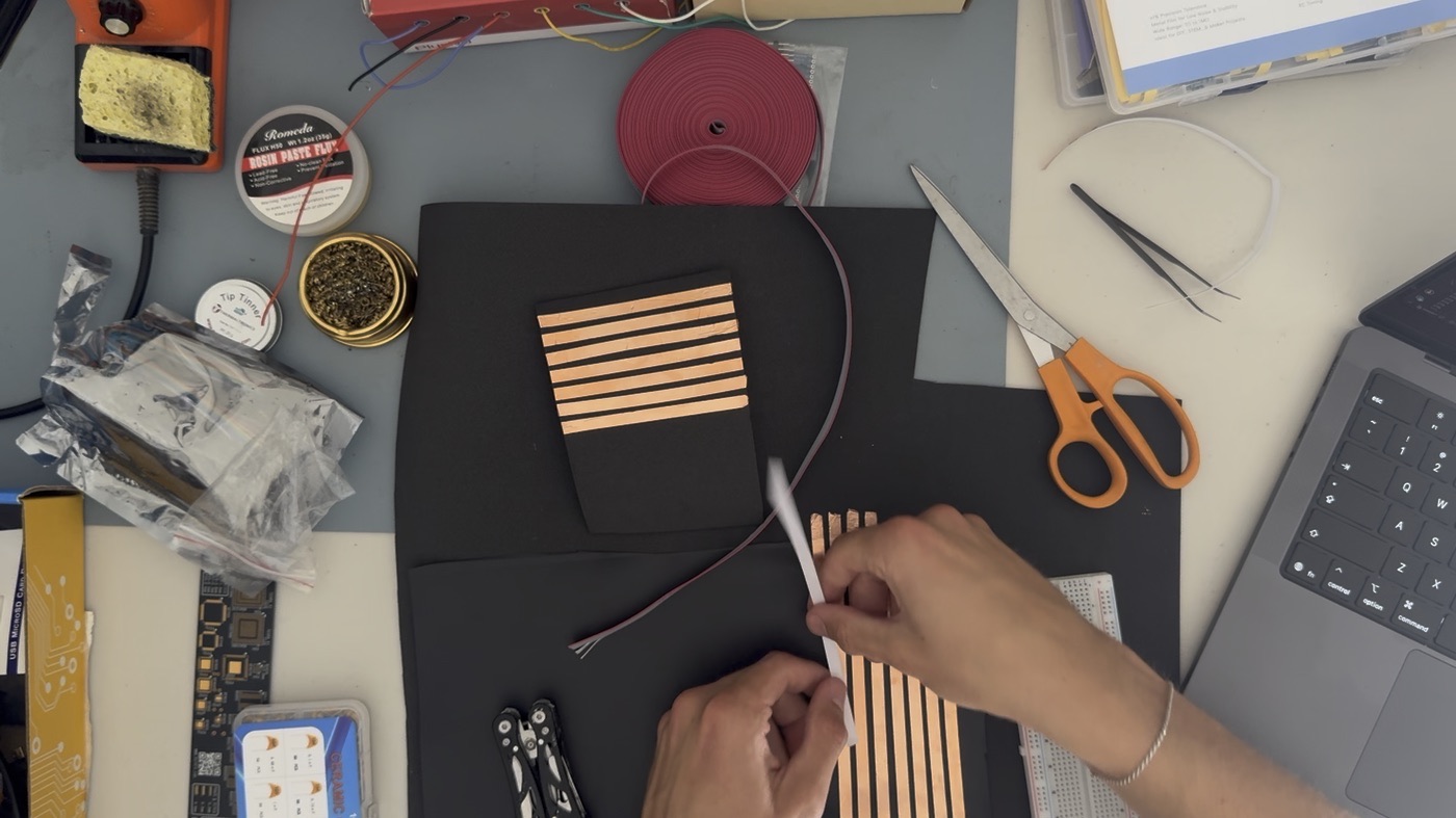 Laying copper tape strips onto black foam sheets