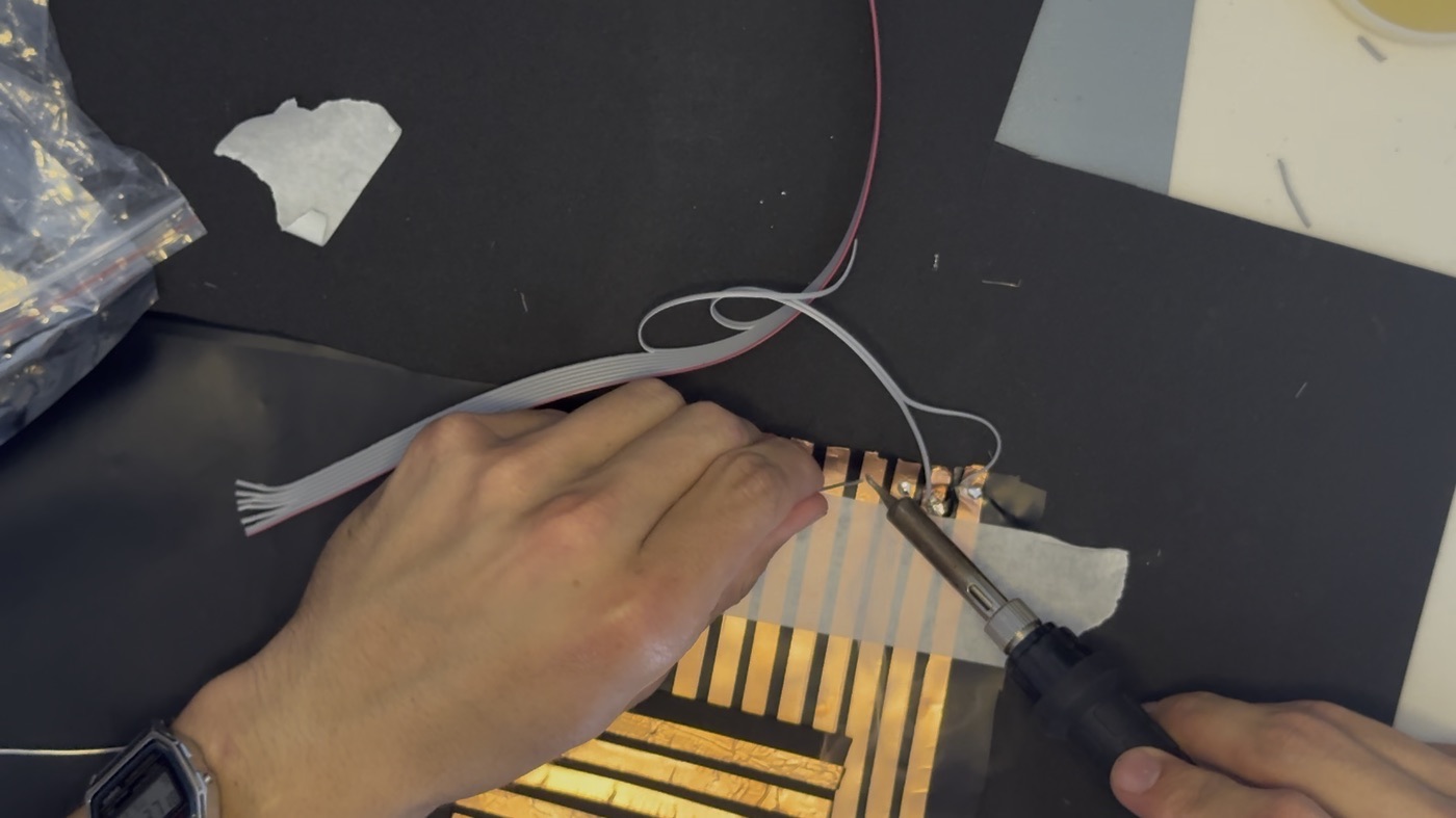 Soldering ribbon cable wires to the ends of the copper strips